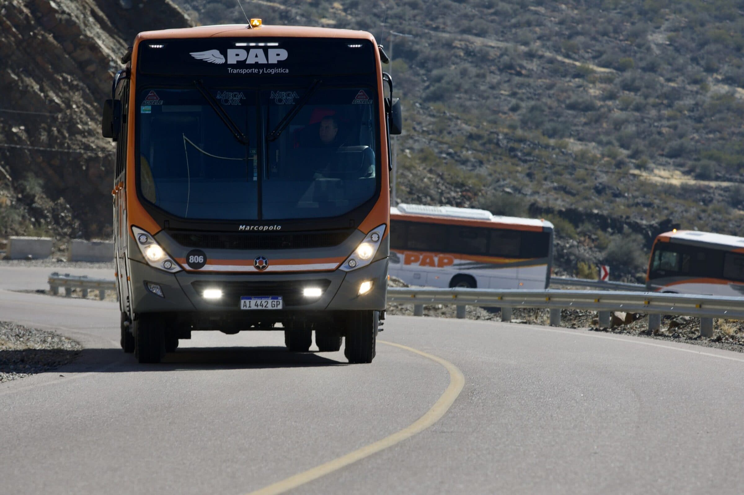 Bus PAP Transporte y Logística de frente en una curva de montaña, seguido por otras dos unidades